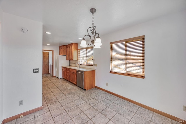 kitchen featuring baseboards, dishwasher, light countertops, freestanding refrigerator, and hanging light fixtures