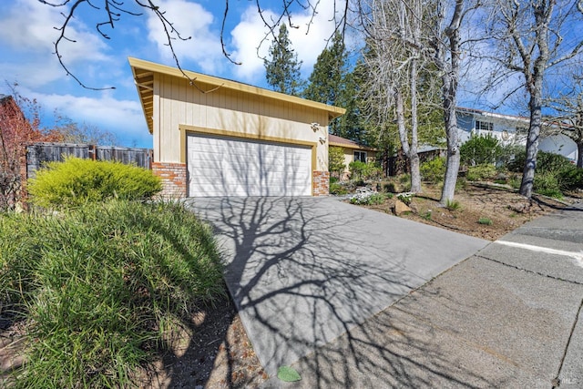 exterior space with a garage, brick siding, and fence