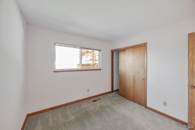 unfurnished bedroom featuring a closet, visible vents, carpet flooring, and baseboards