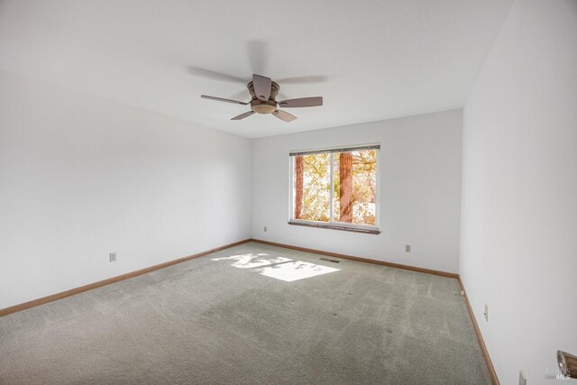 carpeted empty room featuring visible vents, baseboards, and ceiling fan