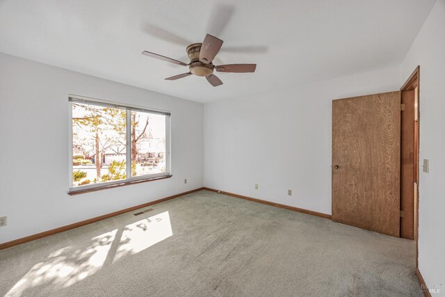 carpeted spare room featuring visible vents, baseboards, and a ceiling fan