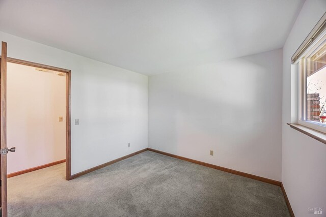 unfurnished room featuring baseboards and carpet