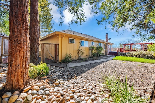 rear view of house featuring a chimney and a wooden deck