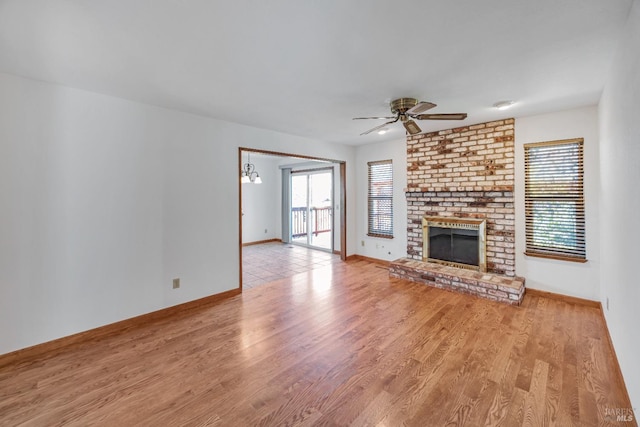 unfurnished living room with a wealth of natural light, a fireplace, a ceiling fan, and wood finished floors