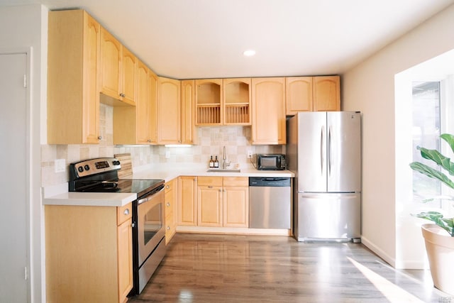 kitchen with light brown cabinets, decorative backsplash, appliances with stainless steel finishes, and a sink