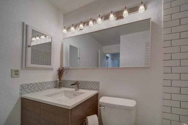 bathroom with backsplash, toilet, and vanity