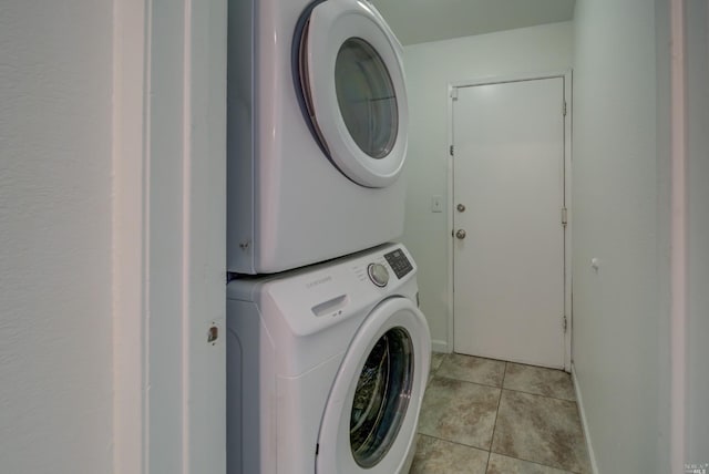 laundry area with stacked washer and dryer, light tile patterned floors, and laundry area