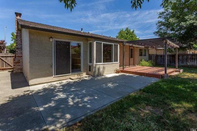 back of property with stucco siding, a pergola, fence, a yard, and a wooden deck