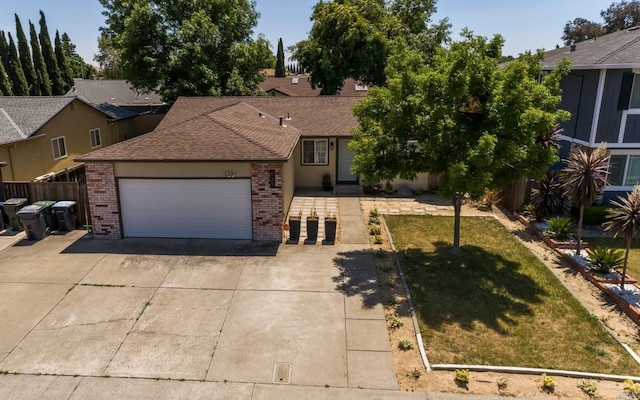 view of front of house featuring a front yard, fence, driveway, an attached garage, and brick siding