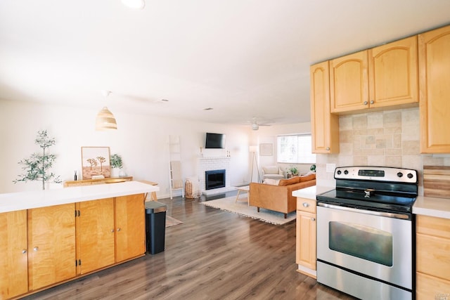 kitchen featuring light brown cabinets, a fireplace, stainless steel electric range oven, and light countertops