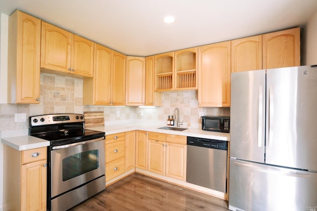 kitchen with light brown cabinets, appliances with stainless steel finishes, and a sink