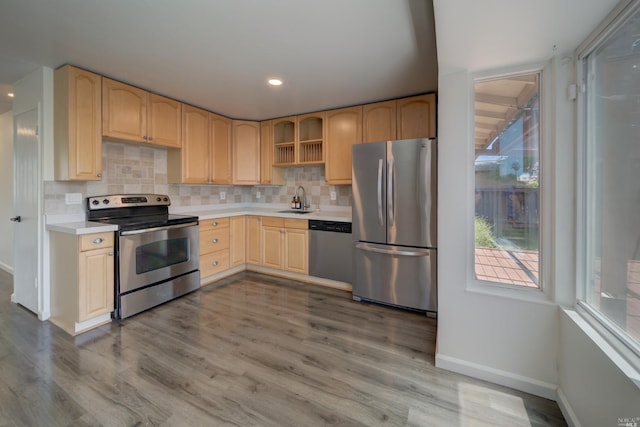 kitchen with light brown cabinetry, a sink, appliances with stainless steel finishes, light countertops, and decorative backsplash