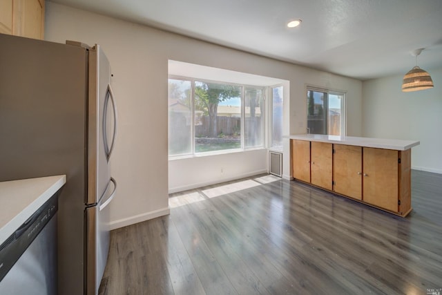 kitchen with stainless steel appliances, a peninsula, dark wood finished floors, and light countertops