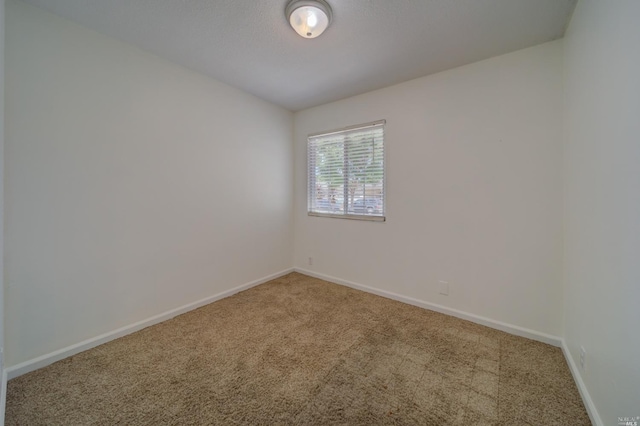 carpeted empty room featuring baseboards