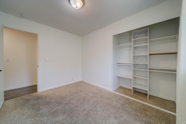 unfurnished bedroom featuring a closet, carpet flooring, a textured ceiling, and baseboards