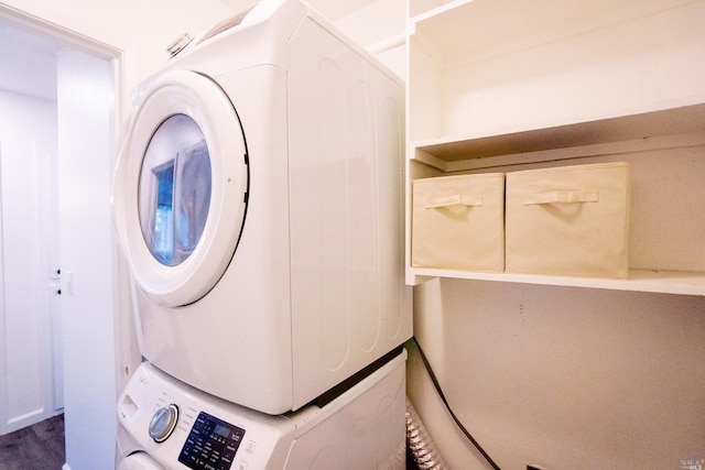 clothes washing area with wood finished floors, stacked washer and clothes dryer, and laundry area