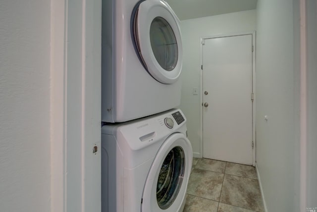 clothes washing area with light tile patterned floors, stacked washer / drying machine, and laundry area