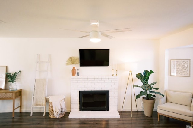 living room with ceiling fan, a brick fireplace, and wood finished floors