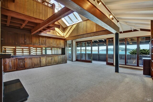 interior space with beam ceiling, a skylight, plenty of natural light, and carpet