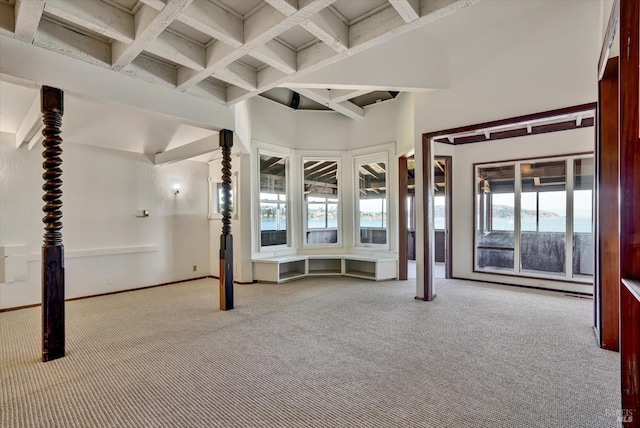 carpeted empty room with a high ceiling, beamed ceiling, and baseboards