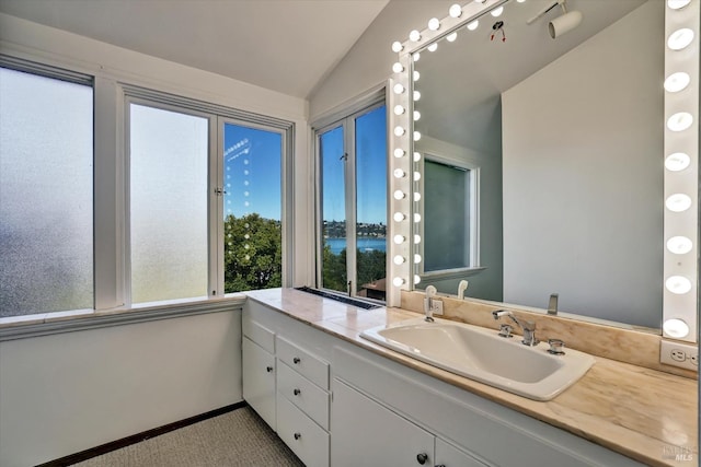 bathroom with vanity, vaulted ceiling, and baseboards