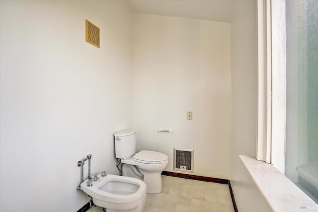 bathroom with tile patterned floors, visible vents, toilet, a bidet, and baseboards