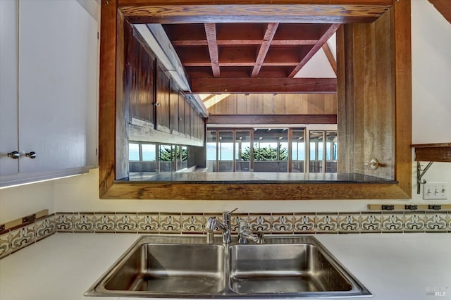 kitchen featuring a sink and vaulted ceiling with beams