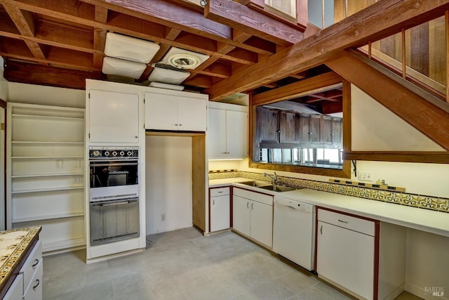 kitchen featuring white appliances, white cabinets, light countertops, and a sink