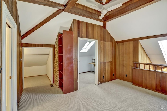 bonus room with vaulted ceiling with skylight, carpet, visible vents, and wood walls