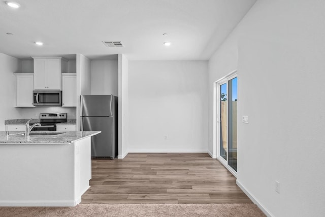 kitchen with visible vents, a sink, white cabinetry, stainless steel appliances, and light stone countertops