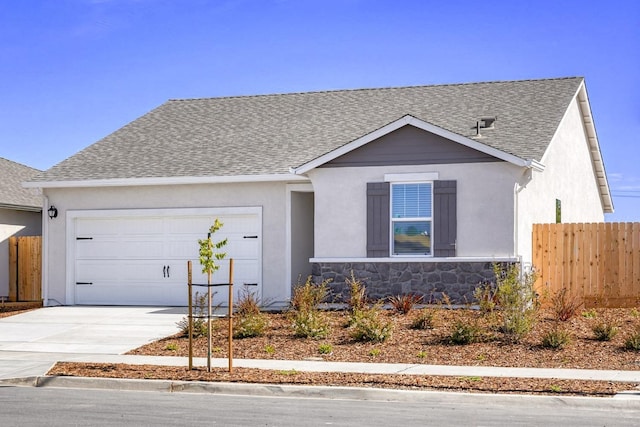 view of front of home featuring fence, an attached garage, a shingled roof, concrete driveway, and stone siding