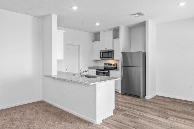 kitchen featuring visible vents, a peninsula, a sink, white cabinets, and appliances with stainless steel finishes