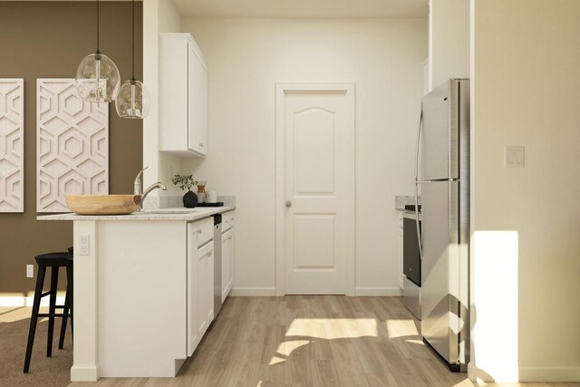 kitchen featuring freestanding refrigerator, a sink, light countertops, light wood-style floors, and white cabinetry