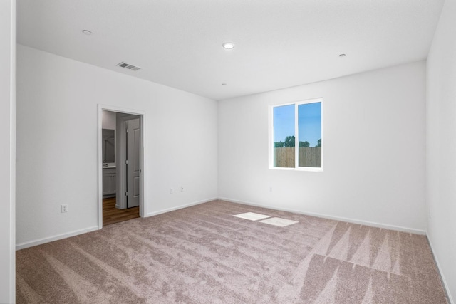 carpeted spare room featuring baseboards, visible vents, and recessed lighting