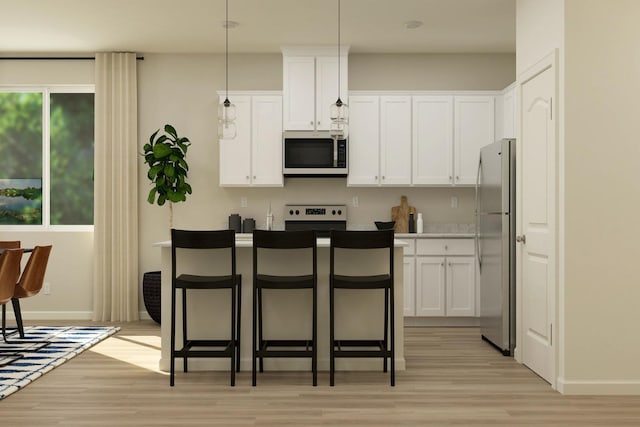 kitchen with a kitchen breakfast bar, white cabinets, stainless steel appliances, and light wood-style floors