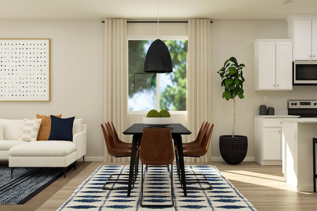dining space featuring light wood-style flooring and baseboards
