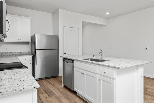 kitchen featuring appliances with stainless steel finishes, an island with sink, light wood-style floors, and a sink