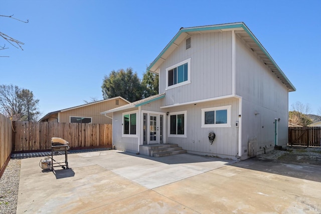 rear view of property featuring a fenced backyard and a patio