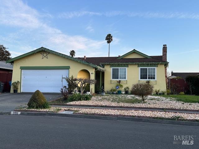 single story home featuring stucco siding, driveway, a chimney, and an attached garage