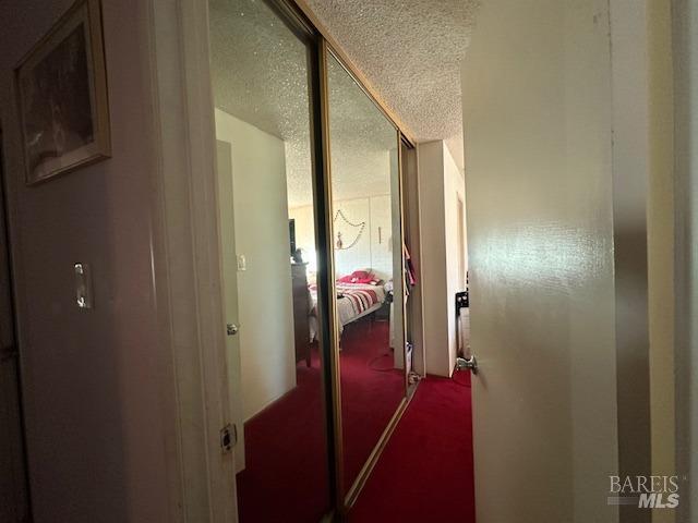 hallway featuring a textured ceiling and carpet