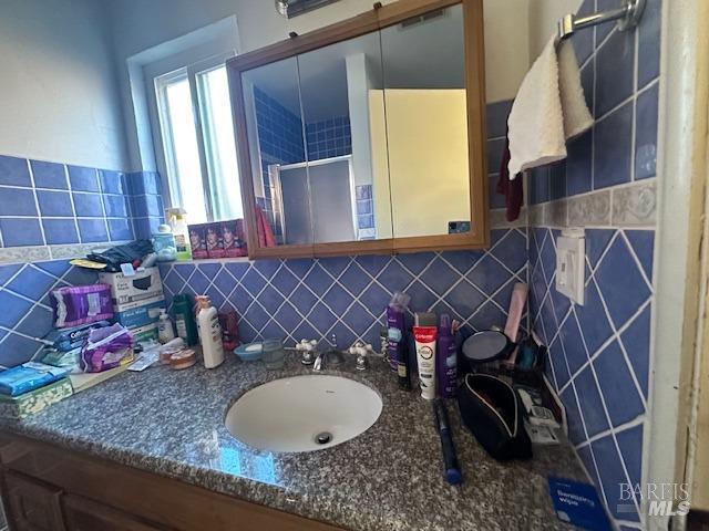 bathroom with vanity, a stall shower, and backsplash