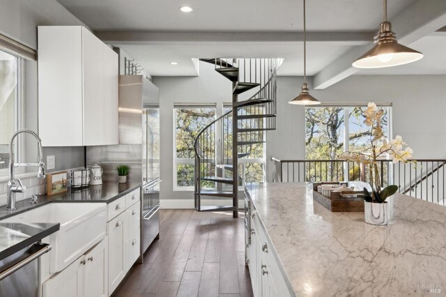 3292 Holland Dr, Santa Rosa, CA 95404 - kitchen with dark wood finished floors, decorative light fixtures, dark stone countertops, white cabinets, and a sink