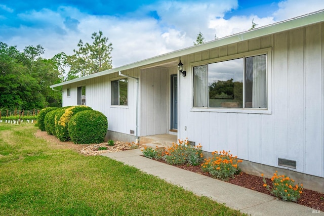 view of exterior entry with a lawn, crawl space, and visible vents