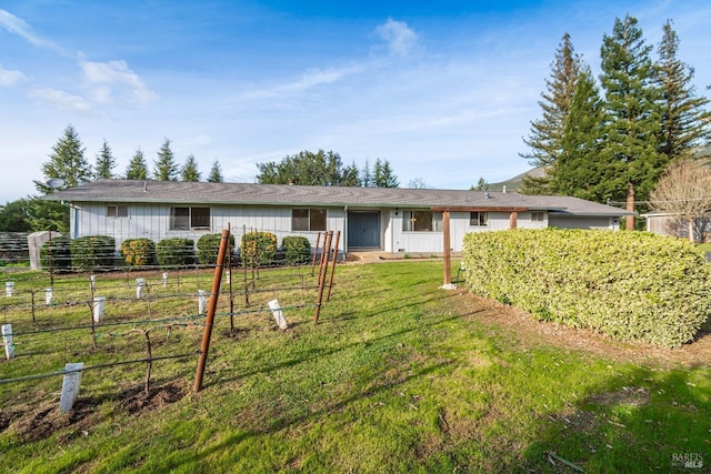 view of front of house featuring board and batten siding, fence, and a front yard