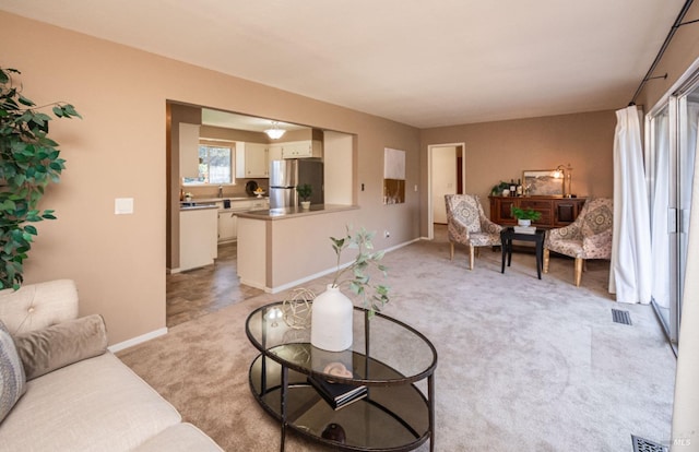 living area with visible vents, light carpet, and baseboards