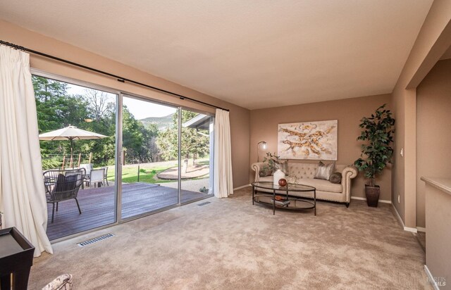 carpeted living room featuring baseboards, visible vents, and a mountain view