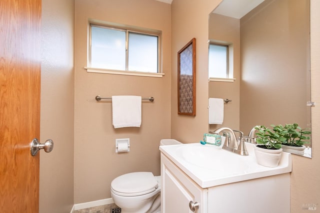 half bath with baseboards, toilet, and vanity