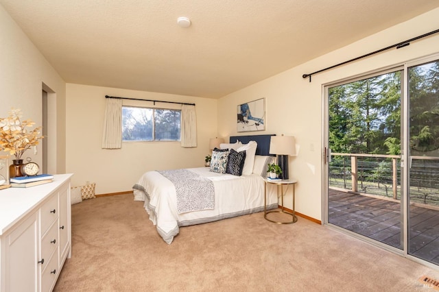 bedroom featuring a textured ceiling, access to exterior, baseboards, and light carpet