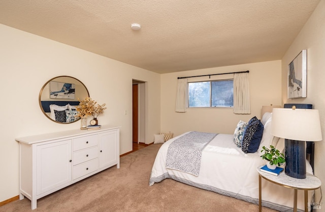 bedroom featuring a textured ceiling, baseboards, and light carpet