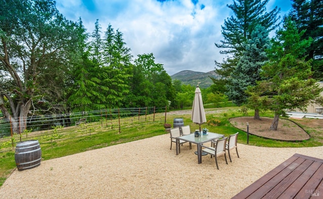 view of patio / terrace with outdoor dining area, a mountain view, and fence